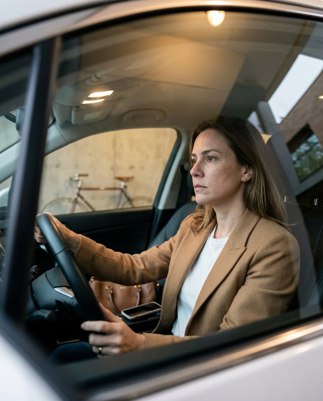 Mulher no carro parado, pensativa, antes de entrar em casa.